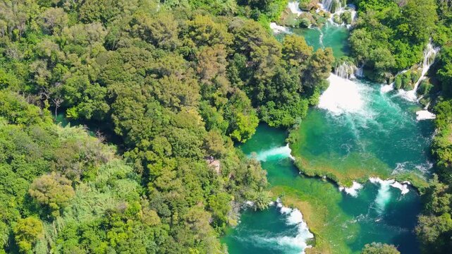 Water falls and green trees view from above in a forested area