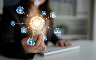 This image portrays a business professional presenting a light bulb surrounded by various icons, symbolizing innovation and technology in today corporate environment. Crux