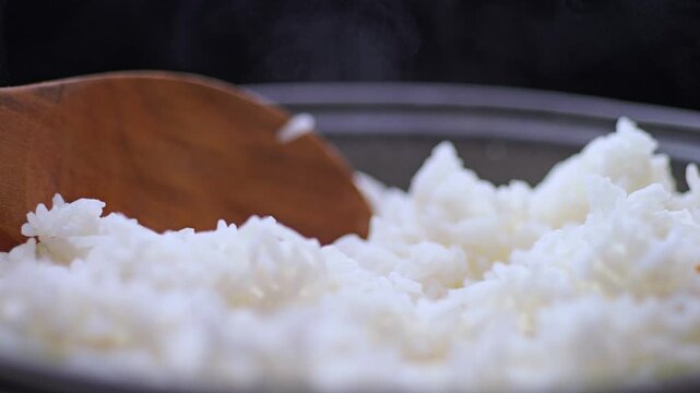 Steamed white rice in a pot with soft steam and wooden spoon, healthy food concept