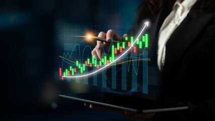 A business professional uses a tablet to analyze digital financial data trends. The image showcases stock market growth and investment insights in a modern office setting. Impute
