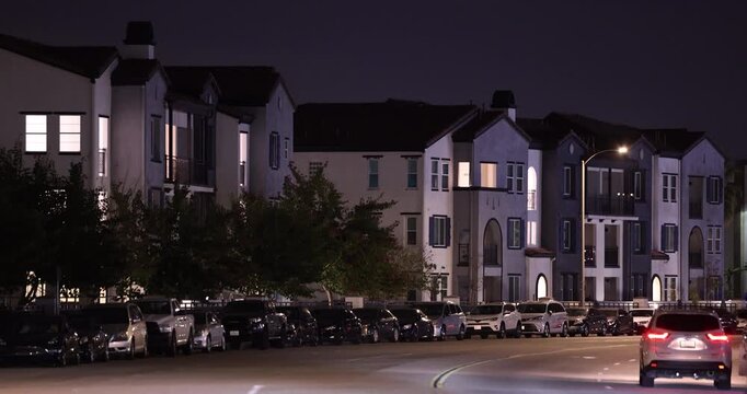 Evening traffic passes on a street in front of dense housing in Chino, California, USA.