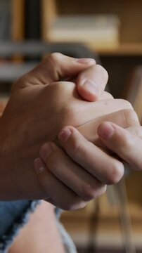 Vertical close up on hands of anxious teen boy fidgeting and clasping together during group therapy meeting at counseling office