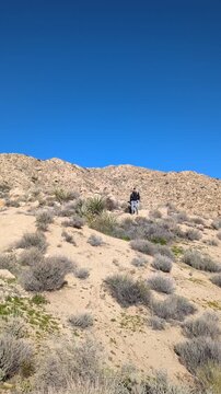 Hiker with backpack tripod hiking along desert ridge trail. Copy space
