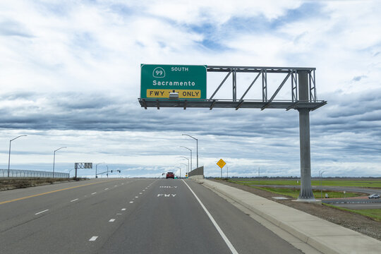 Road sign directing drivers to Sacramento on Highway 99 south in Elverta, California showing truck driving route and road conditions
