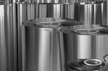 a bunch of rolls of aluminum metal. thin metal. standing side by side.