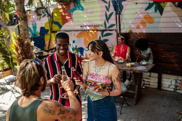 Friends toasting drinks at a colorful outdoor patio