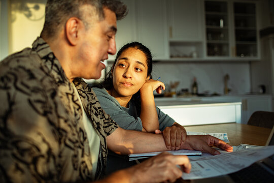 Man and young woman discussing household finances at kitchen table