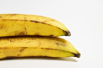 Close-up of two ripe bananas with yellow peel on white background