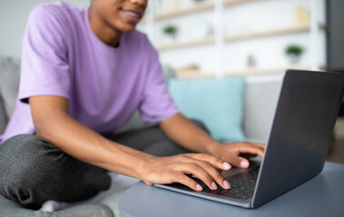 E-learning concept. African American adolescent studying online, typing on laptop at home, closeup...