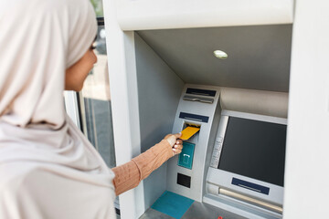 Currency, finance and transactions. Lady inserting an bank credit card into ATM machine to transfer...