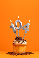 Birthday candle number 104 - Invitation card with orange background. Cupcake