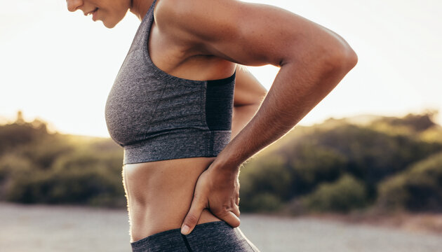Woman holding her lower back in discomfort during workout