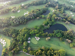 Aerial view of golf course fairway and green with sand traps pond and trees