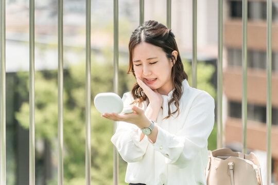A woman complaining of jaw and tooth pain while looking in the mirror (temporomandibular joint disorder, tooth decay, periodontal disease, oral and facial pain, stiff neck, toothache, stress)