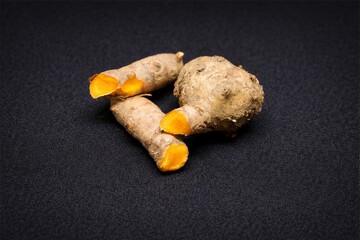 Turmeric Root Rhizomes with Vibrant Orange Flesh Isolated on Dark Background