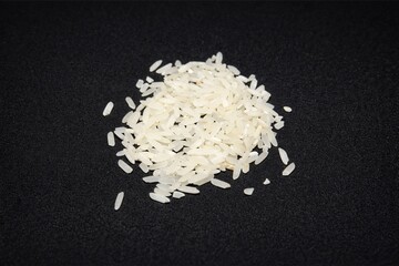 Heap of Raw White Rice Grains Isolated on Dark Background