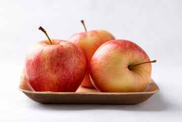 Red apple fruit (Gala apple) in natural plate on white background