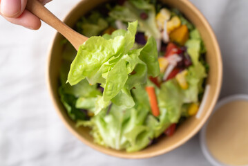 Healthy vegetable salad bowl with hand holding fork for eating, Top view, Close up