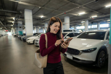 Woman smiling using smartphone finding car in parking garage