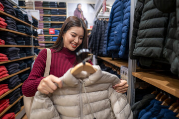 Asian woman shopping for casual jacket in retail store
