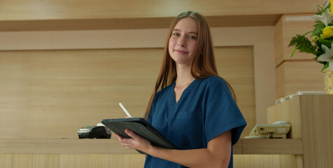 A young female doctor is preparing to examine a patient using a digital tablet while working (Photo)	