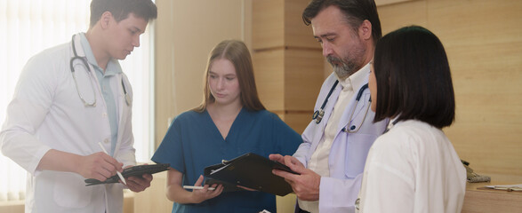 A group of doctors, nurses and staff pose for a photo in a hospital corridor.	