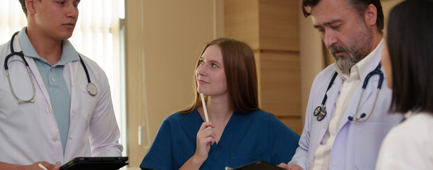 A young female doctor is preparing to examine a patient using a digital tablet while working (Photo)	