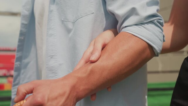 man woman holding picnic basket on rooftop during sunny afternoon, woman gently wraps arm around mans forearm while man grips woven basket, casual denim shirt, warm light, candid romantic moment,