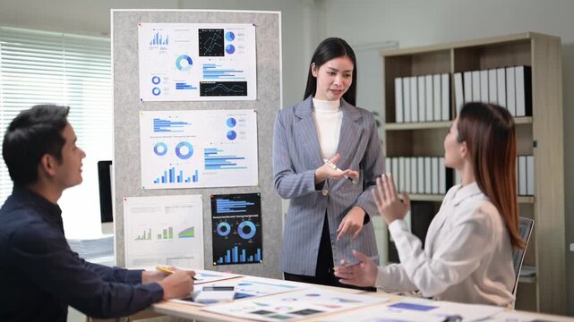 A woman is giving a presentation in front of a group of people. There are three people in the room, one of whom is a man