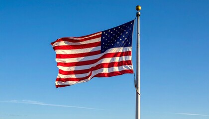 A vibrant American flag with red and white stripes and blue field with white stars, waving proudly on a flagpole against a clear, bright blue sky.