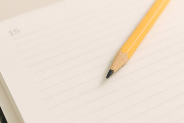 Close-up of pencil on lined notebook with blurred background.