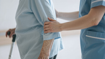 Obraz premium nurse-supporting-senior-patient-walking-with-cane-hospital