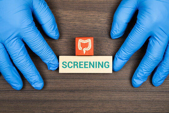 Doctor's hands stacking wooden blocks with a large intestine icon; concept of colon cancer prevention, early diagnosis, and digestive health. Screening