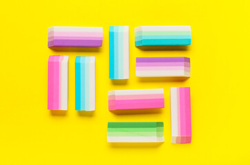 Fototapeta premium Many colorful rubber erasers on yellow background