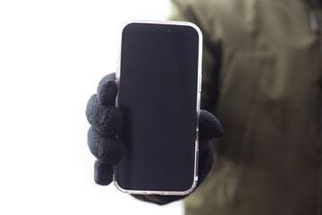 Hand in black glove holding mockup modern smartphone with black screen isolated on white background. Concept of mobile technology, winter use, online communication and digital lifestyle.
