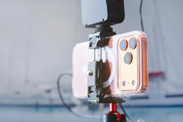 Smartphone mounted on tripod with external microphone for video recording. Mobile content creation setup for vlogging, blogging, streaming, social media, online education and podcasting.