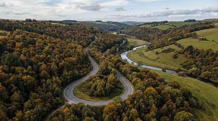 Winding horseshoe bend road and river wye flowing through the green and autumnal wye valley landscape with rolling hills, aerial view