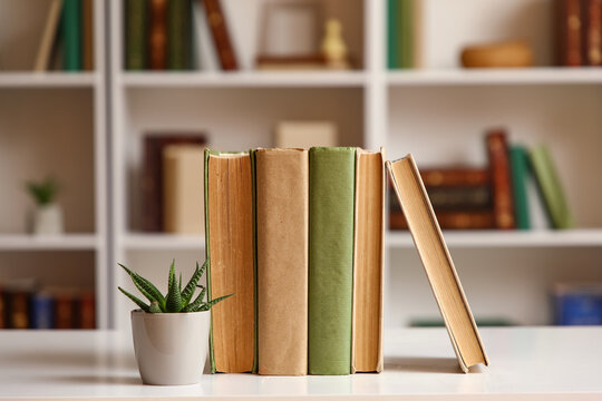 Books with plant on table in home library, closeup