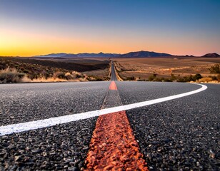 An open road stretches towards distant mountains under a dusky sky