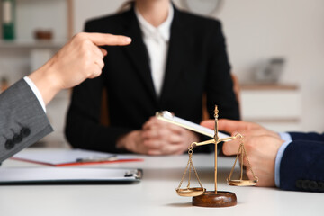 Justice scales against mediator with clients at table in office, closeup