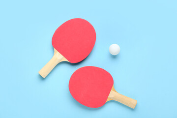 Ping pong rackets and ball on blue background