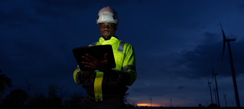 Technicians and engineers are working at a wind power plant at sunset. Renewable energy solutions to address climate change; clean energy at wind farms.