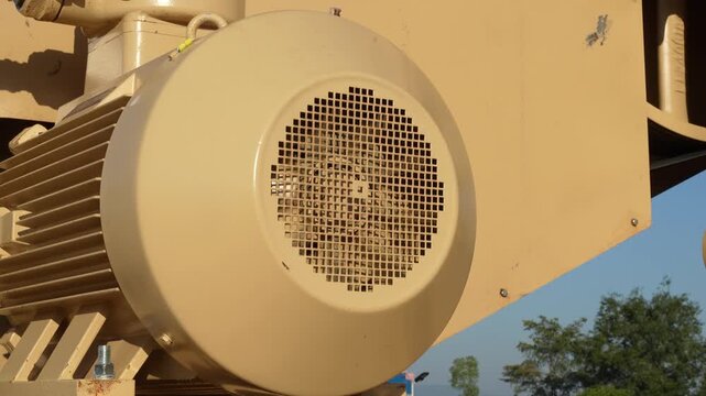An electrical motor of pumping machine unit is rotate during it operating. Industrial equipment part, close-up and selective focus.