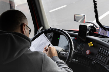 Driver reviews documents while operating truck on highway in Pleasant Grove California © Liana