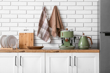 Modern coffee machine, electric kettle, clean plates and napkins on counter in kitchen