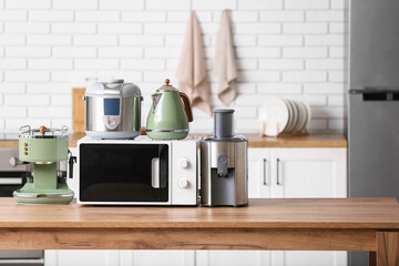 Different modern household appliances on wooden table in kitchen