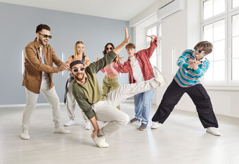 Group of young men and women wearing trendy casual outfits, moving to music, enjoying energetic dance session in stylish urban dance studio. Contemporary hobby, urban dance community spirit concept