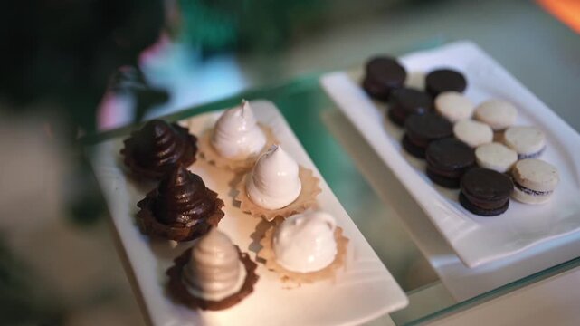 Sweet table display with gourmet desserts arranged neatly for elegant celebration or reception, white and black pudding and macaroons