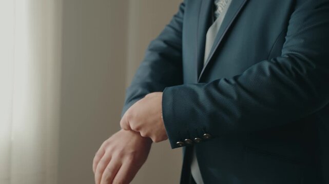 Close up of groom adjusting suit sleeve and cuff before ceremony