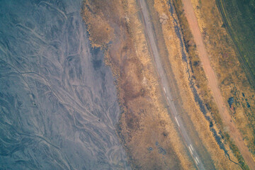 Industrial waste sludge near road and green field, toxic ground boundary, environmental pollution vs agriculture concept, aerial drone shot top view